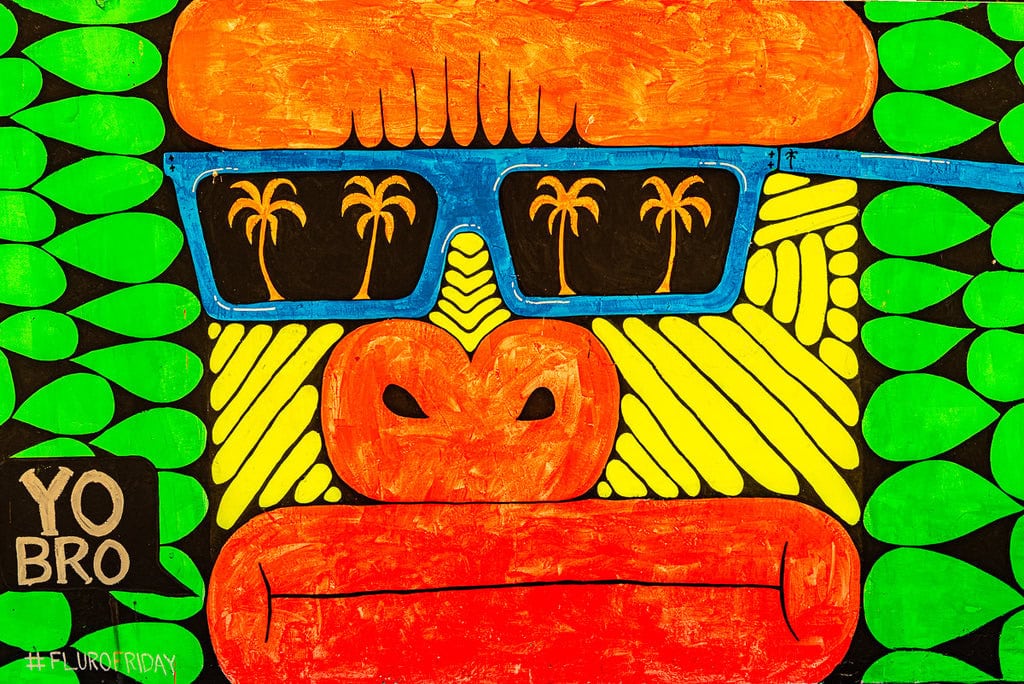 Bright and colorful mural of a gorilla wearing sunglasses reflecting palm trees.