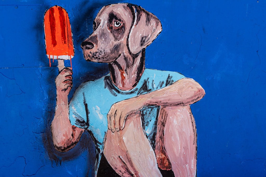 Graffiti mural of a dog holding a red popsicle.