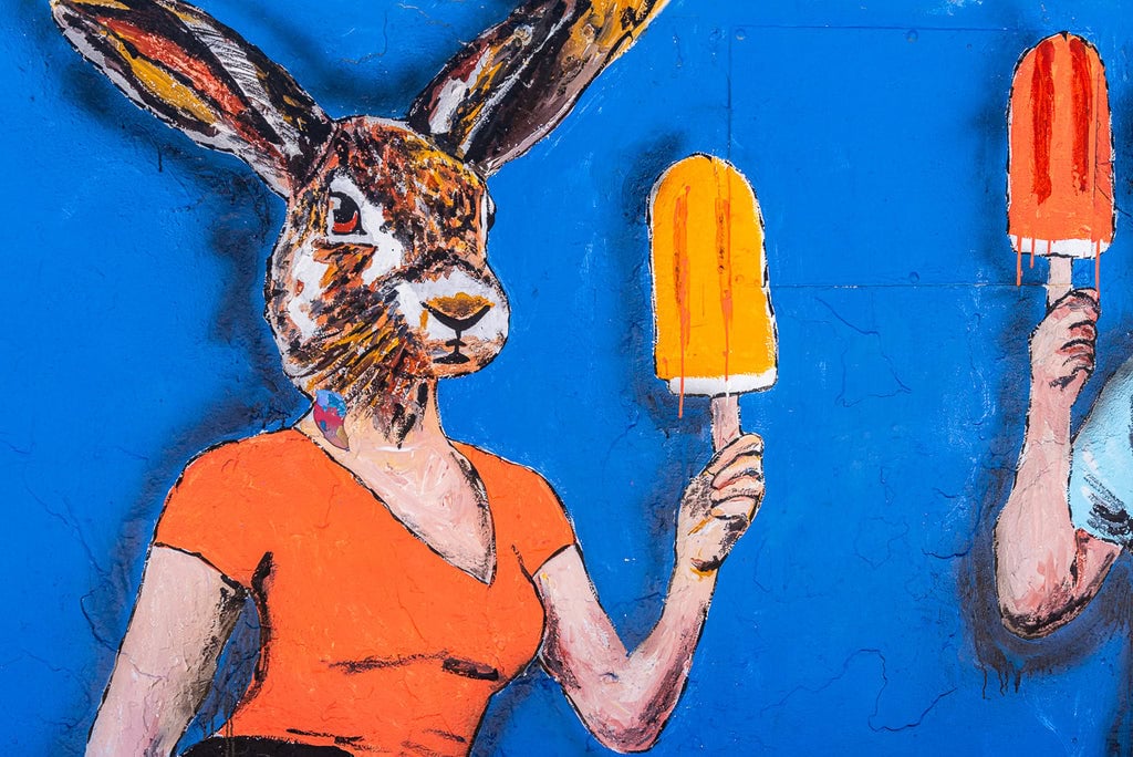 Street art featuring a rabbit holding an orange popsicle.