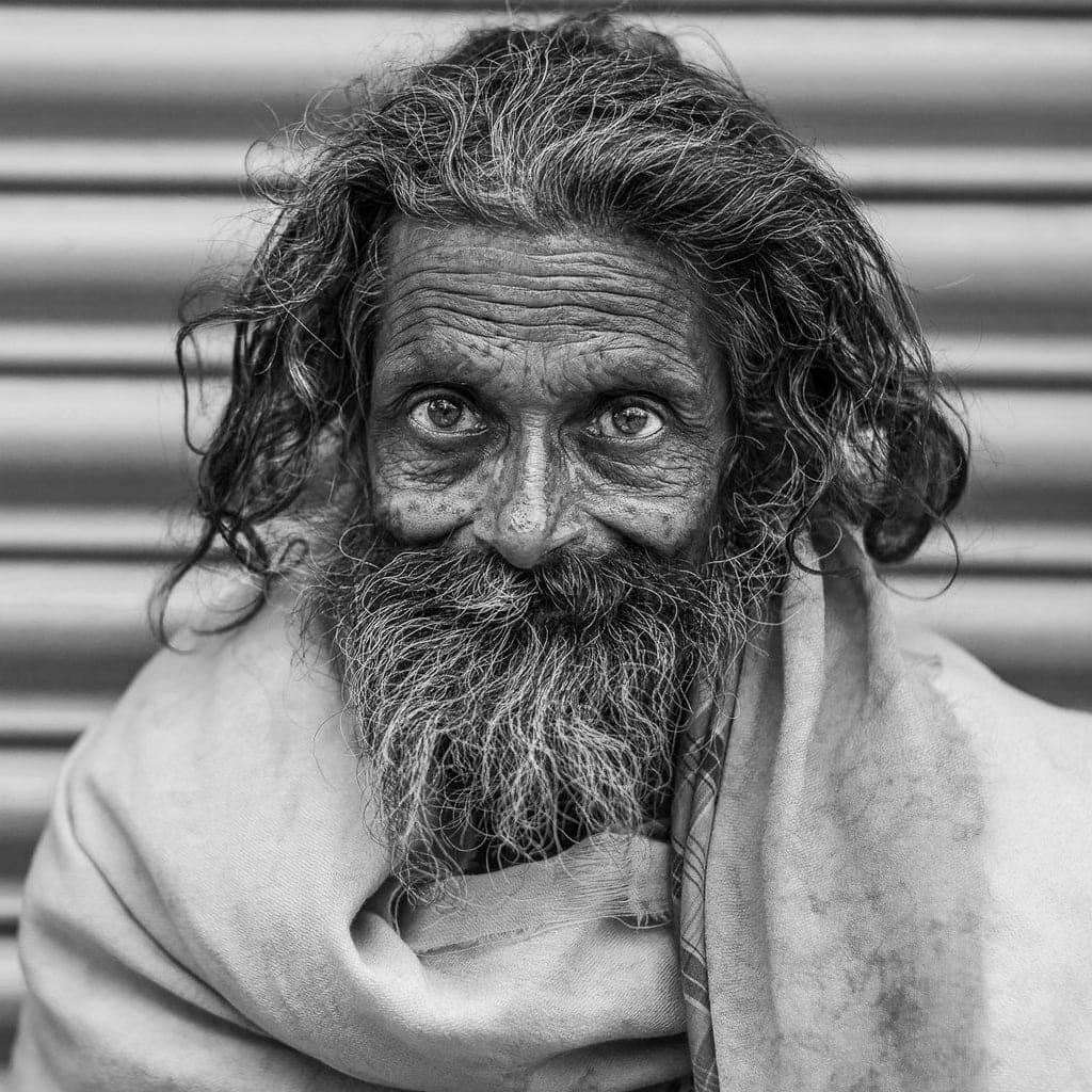 This close-up portrait captures the deep lines and intense gaze of an elderly man in India—showing how getting close allows you to connect with your subject on a profound, intimate level.