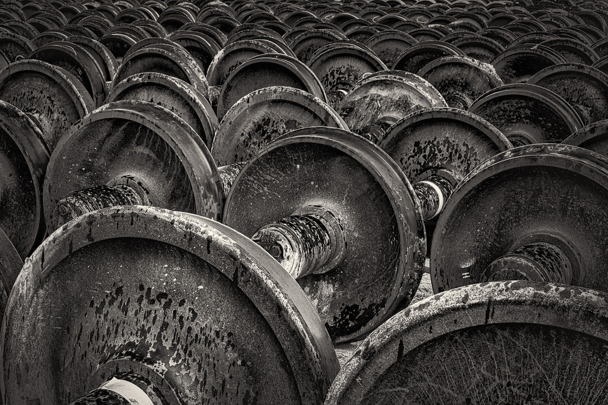 Circular echoes of movement now halted—these rusted wheels rest beneath the weight of time and forgotten tracks.