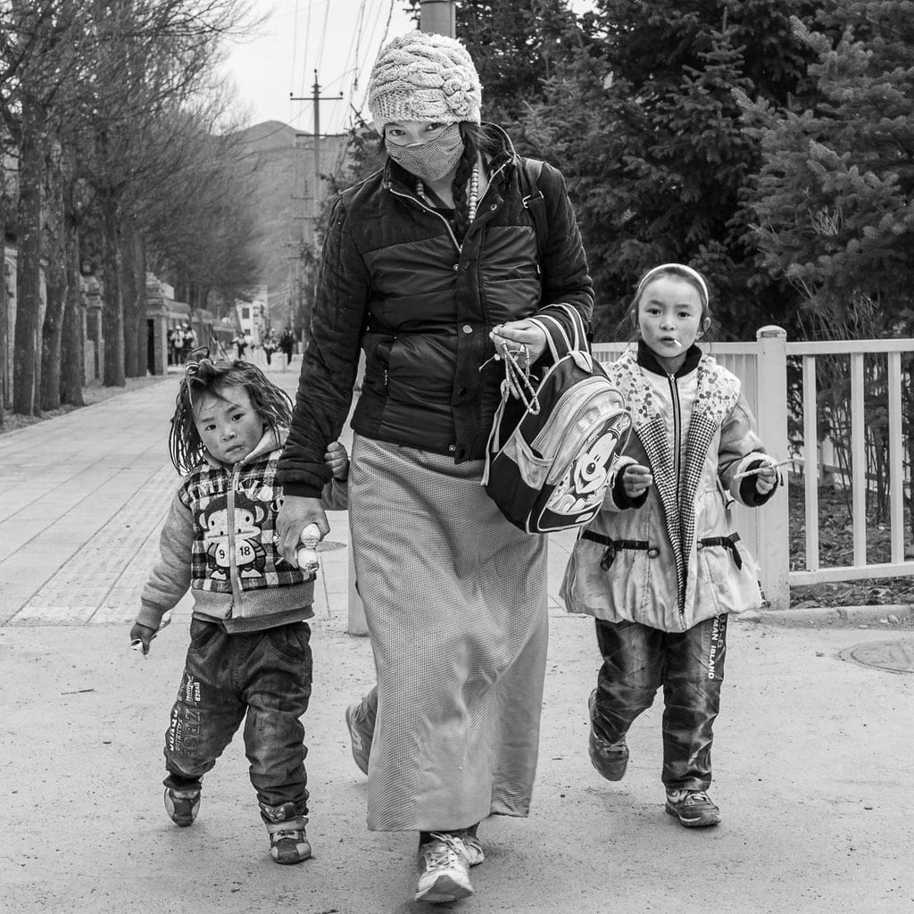 Captured while matching the pace of the street, this moment shows a Tibetan mother and her daughters moving with purpose through their day—illustrating how blending into the rhythm of the environment can reveal powerful, everyday stories.