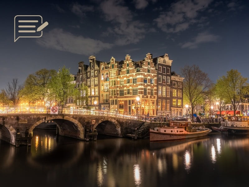 A peaceful summer evening in Amsterdam, with the canals reflecting the warm glow of the city’s lights.