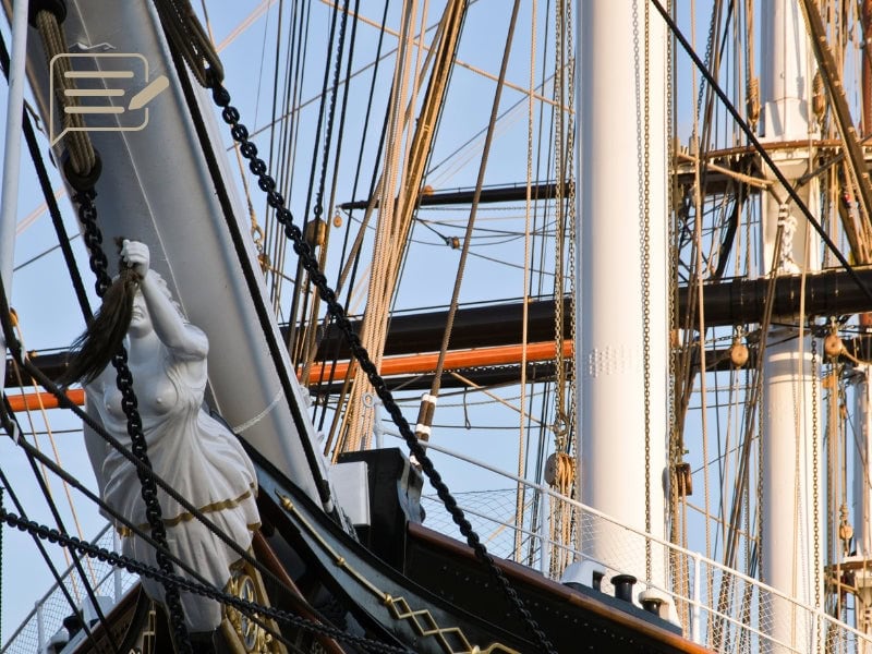 A close-up of the Cutty Sark’s elegant figurehead, framed by her intricate rigging and majestic masts. This iconic sculpture embodies the spirit of adventure and exploration that the ship represents.