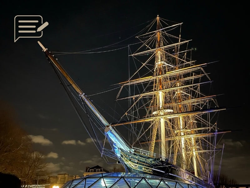 The Cutty Sark illuminated under the night sky, her rigging and masts beautifully lit, creating a striking silhouette against the darkness of Greenwich.