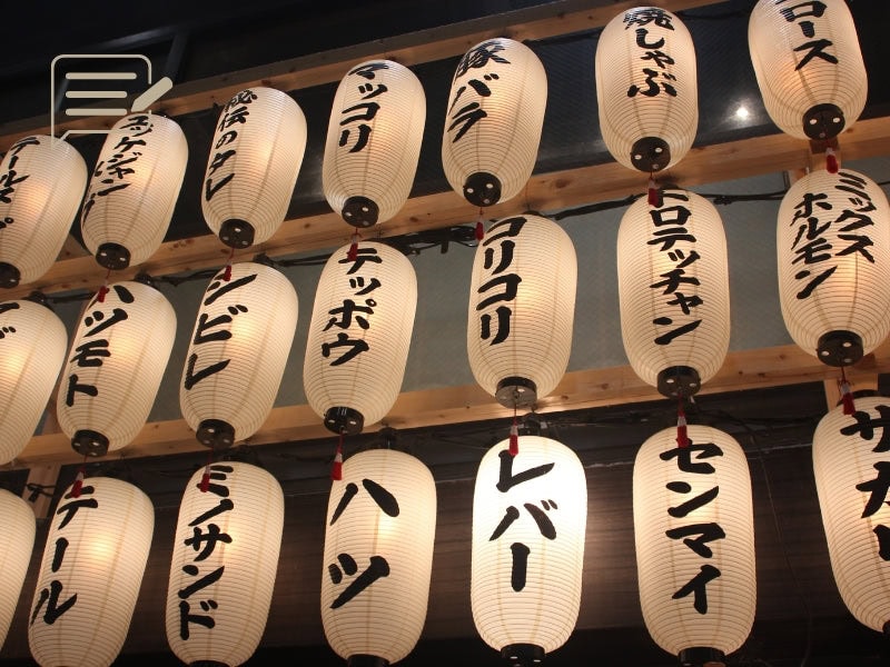Rows of illuminated Japanese paper lanterns at a bustling night market, each one inscribed with traditional characters.
