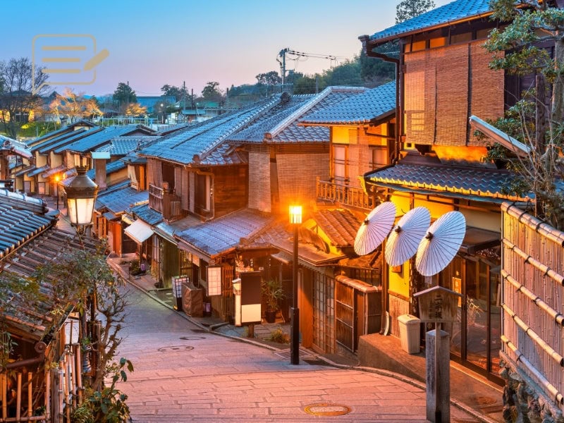 A serene traditional Japanese street illuminated by warm evening lights, showcasing the charm of Kyoto’s historic neighborhoods.